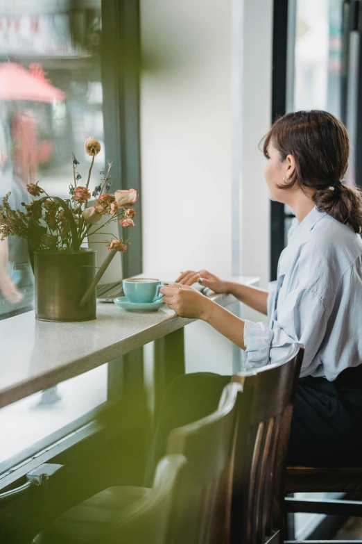 a woman is drinking from a cup at a table