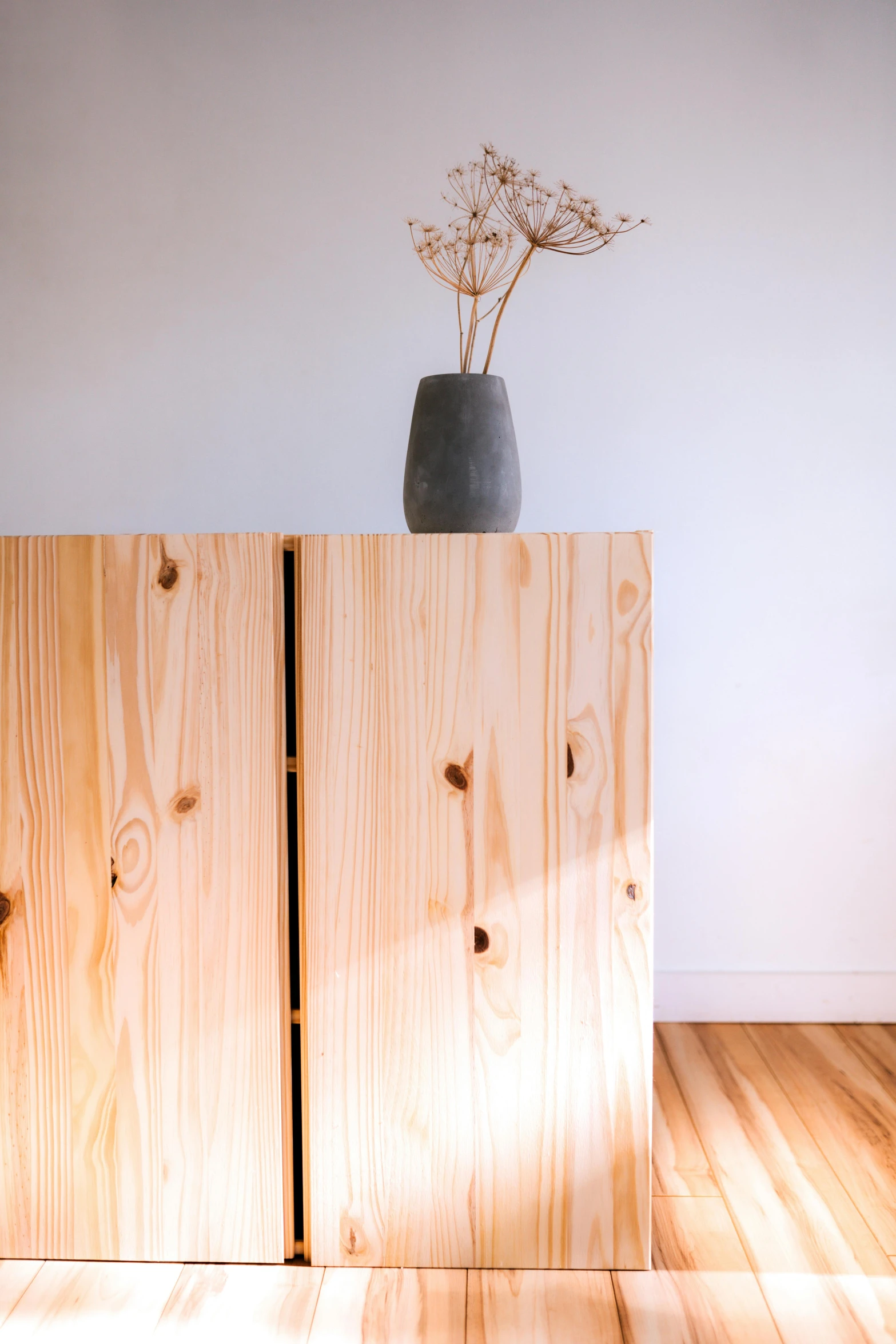 two cupboards with wood doors and a vase with flowers on top