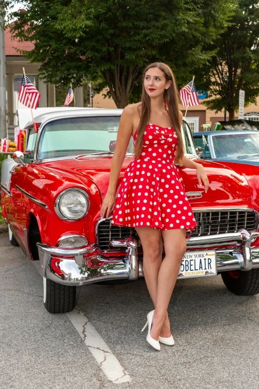 a woman posing next to an old fashioned red car
