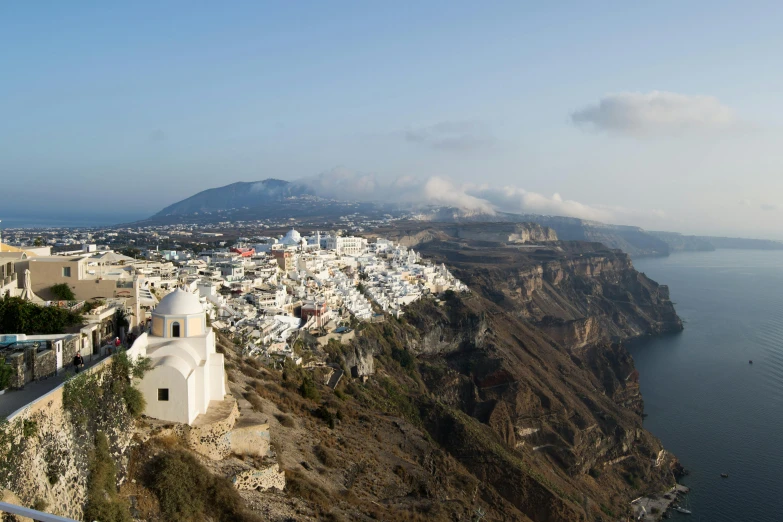 a cliff top is shown, overlooking a small town near the sea