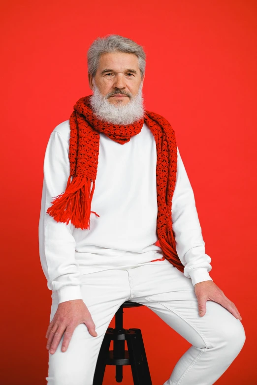 a bearded man wearing white pants and a red scarf