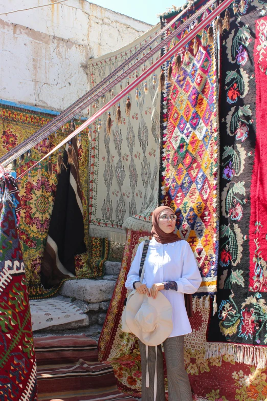 woman standing on street near a number of colorful carpets