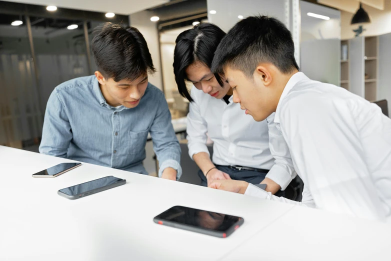 three young asian business people are looking at cell phones