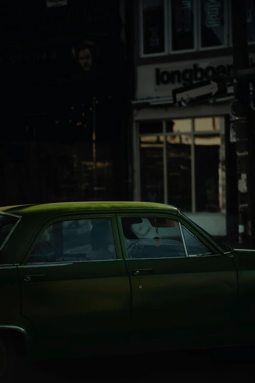 an old green car is parked on the side of the road