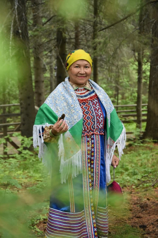 a woman dressed in native dress with a bush and other woods