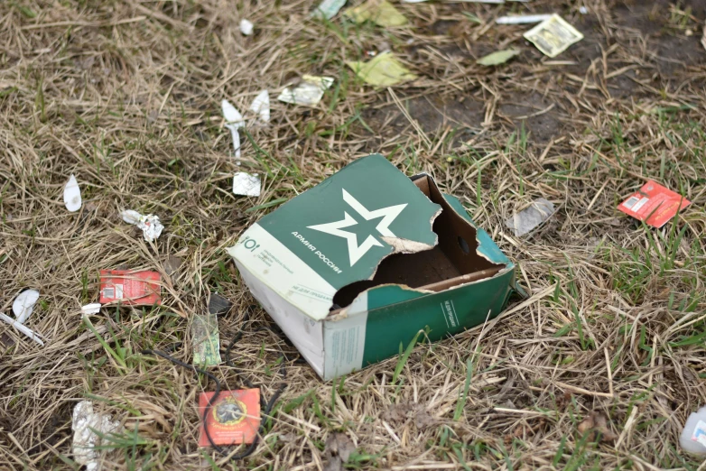 a box with a green and white star sitting on a grass covered field