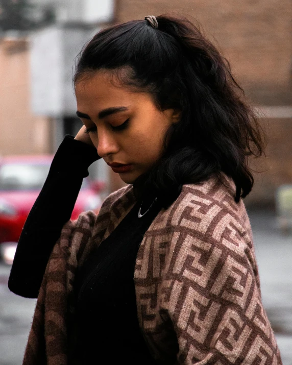 a woman holding her hand on to her head walking down the street