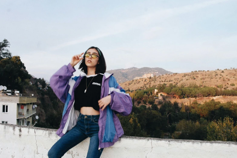 woman standing on top of a high wall posing for a po