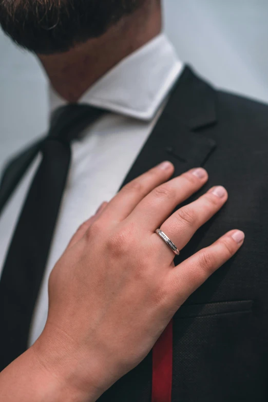 a hand with a ring on it next to a tie