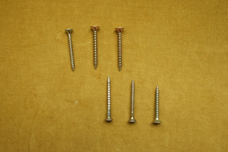 screws lying next to each other on a tan background