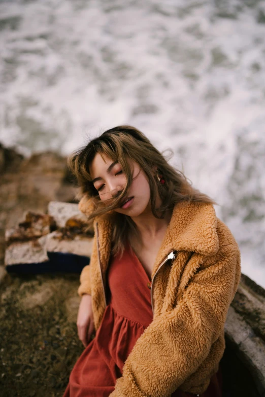 woman sitting on the edge of a cliff overlooking water