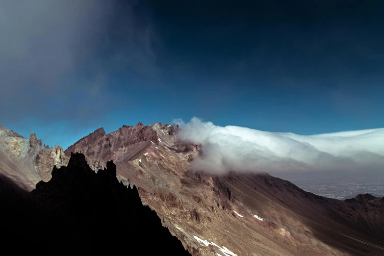 some clouds are hanging over a mountain side