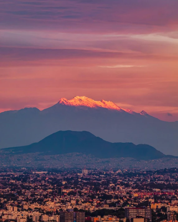 the snowy mountain behind a city is silhouetted