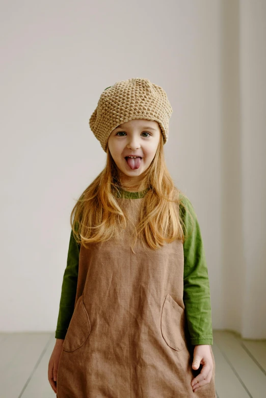 a child wearing a hat and a apron on a tile floor