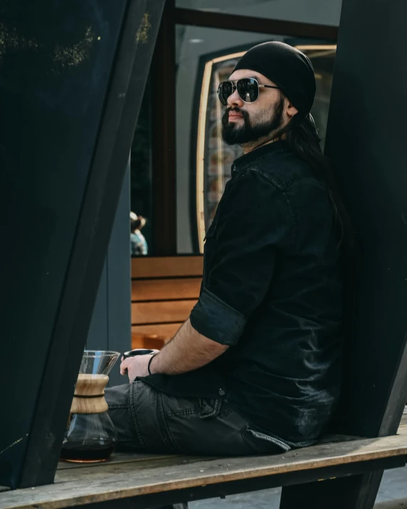 a man with a beanie sitting outside next to some doors