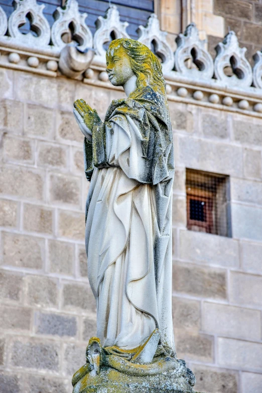 a statue of an angel stands in front of a large brick building