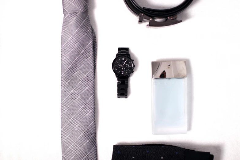 a tie, watch, and tie clip on a table