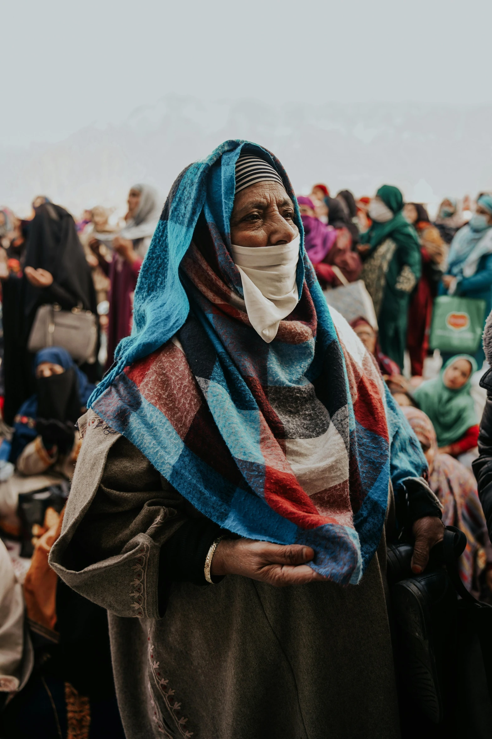 an old woman wearing a scarf with a bunch of people sitting around her