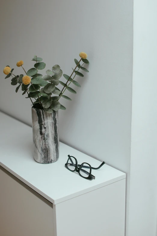 a vase with flowers sitting on a small counter