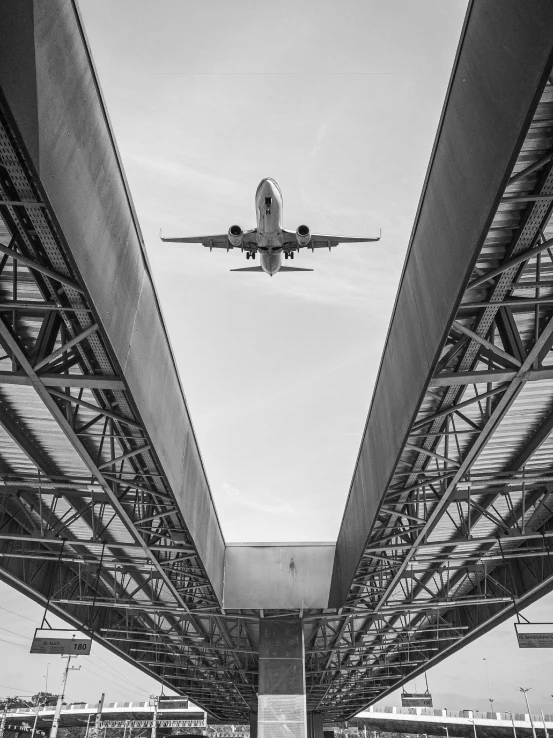 a large airplane flying low over a bridge