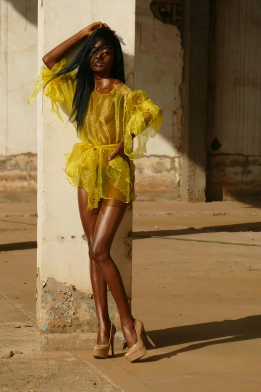 a very pretty lady standing by a tall pillar