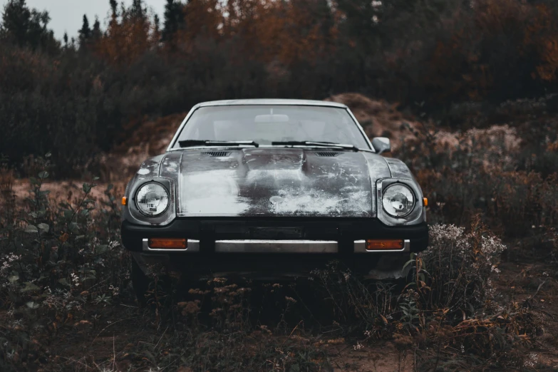 the front view of an old rusty car in a field