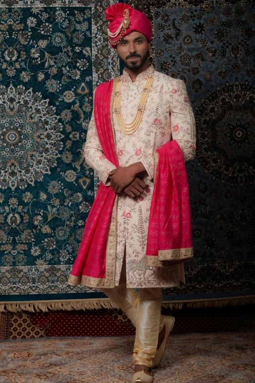 a man in an indian bridal outfit poses for the camera