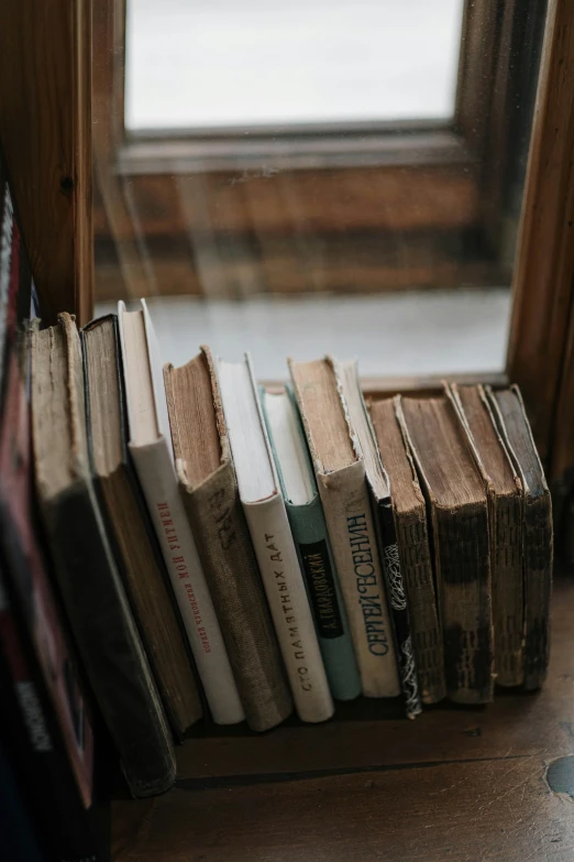 several books on a shelf in front of a window