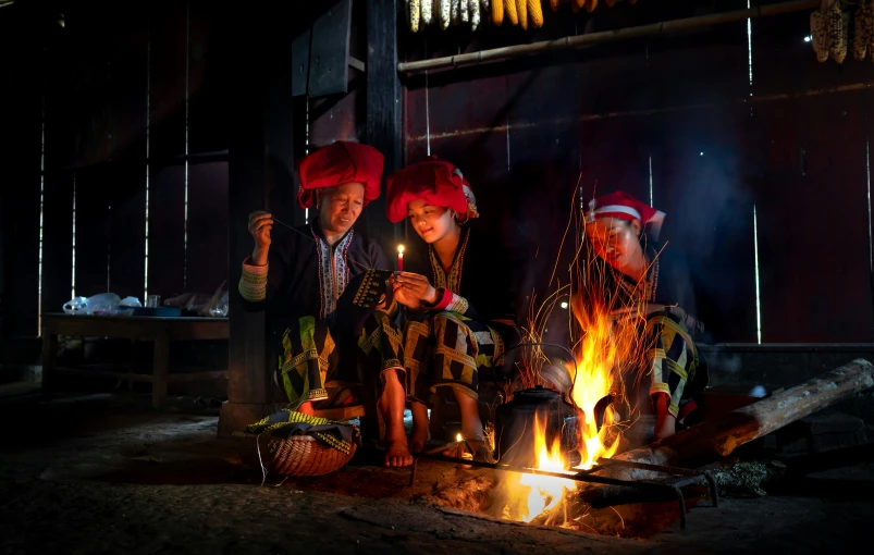 three people in halloween costumes sitting around a campfire