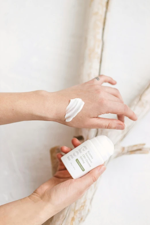 a woman touching her hand while applying an eye cream on her arm