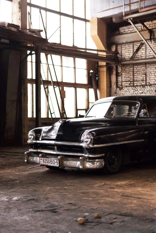 an old black car with a flat bed sits in a rusted room