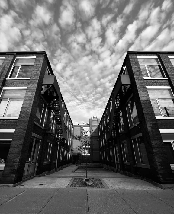 two buildings with windows next to each other under cloudy skies