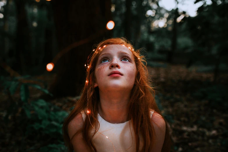 a girl is staring up at the camera in a forest