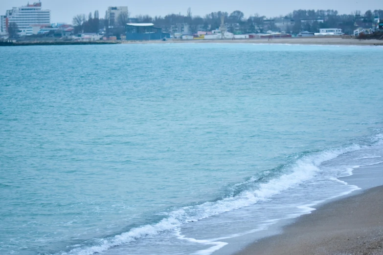 a person standing at the edge of a beach by the water