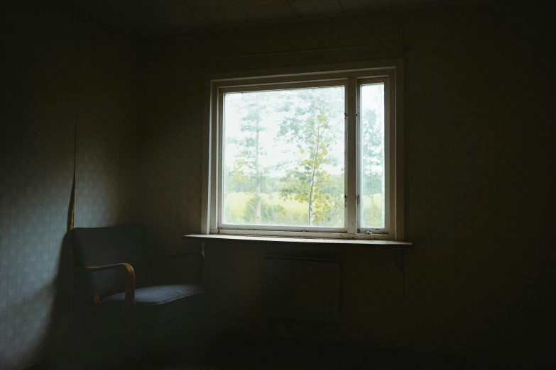 a dark room with the window open showing soing green