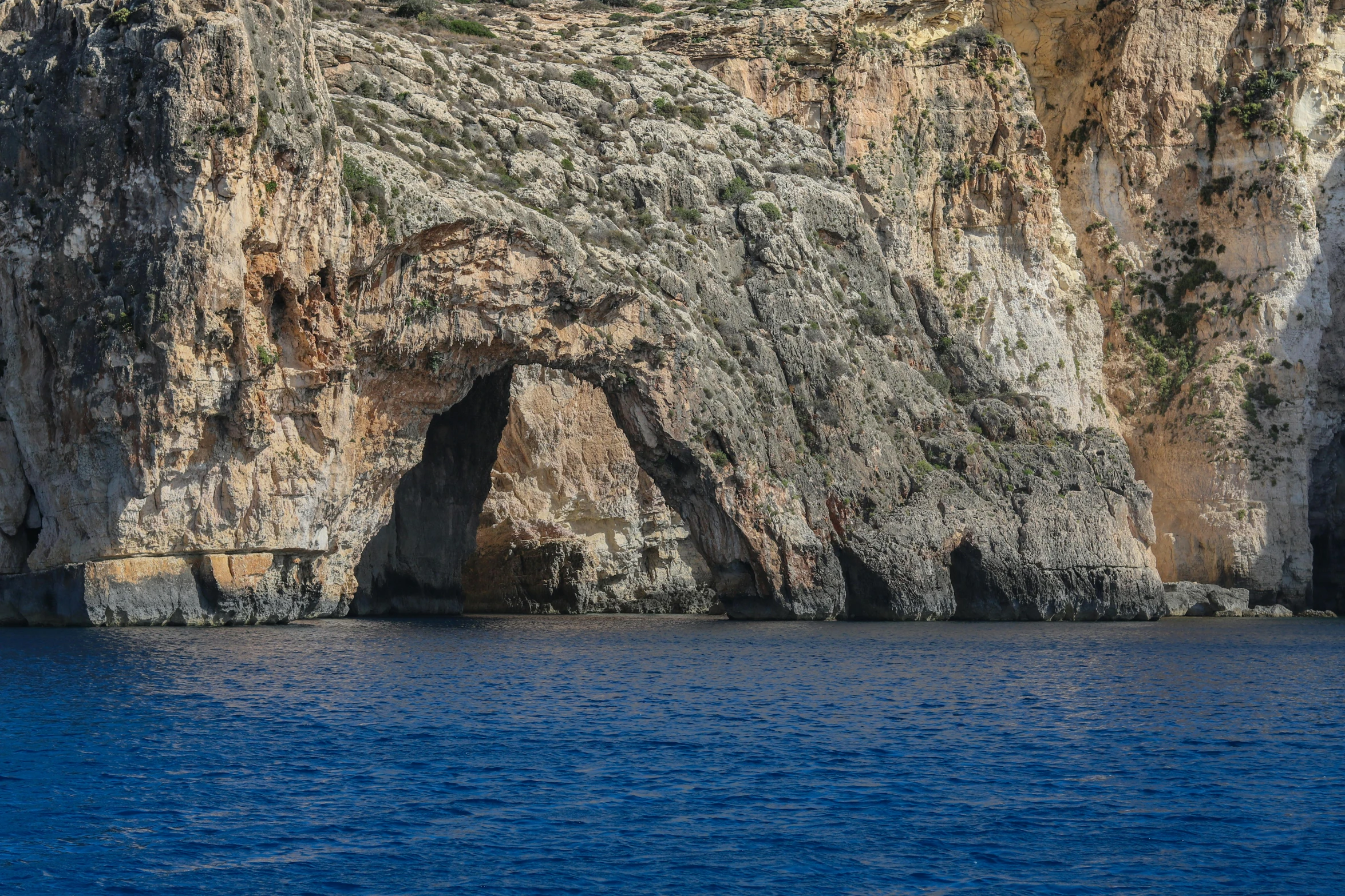 an image of a cave on a cliff above water