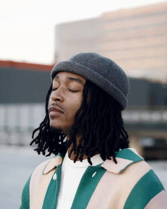 man with dreadlocks wearing green and white striped sweater