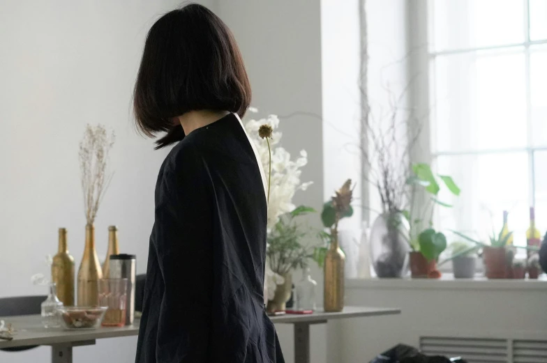 woman standing next to window wearing a black suit