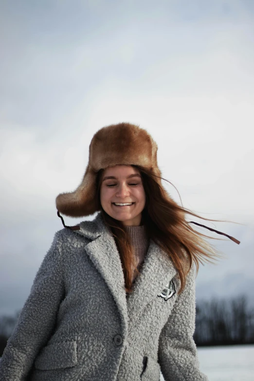 smiling woman in grey coat and fur hat