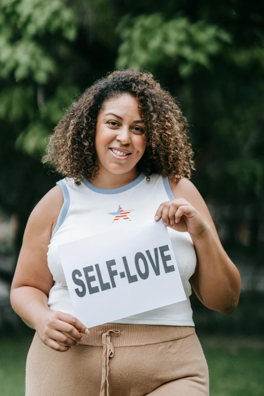 an image of a woman holding a self love sign