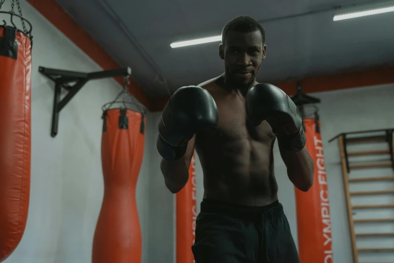 a man standing in a boxing ring next to punching bags