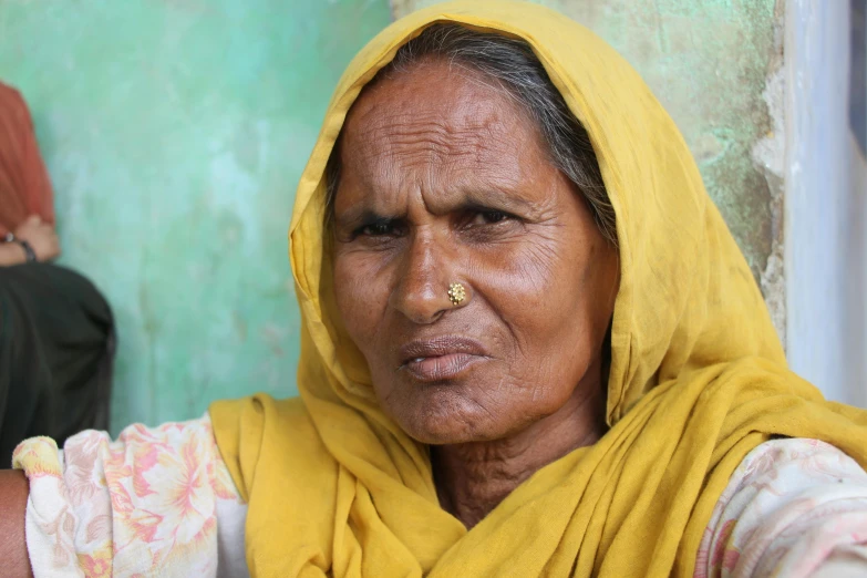 an older woman in yellow cloths and some people