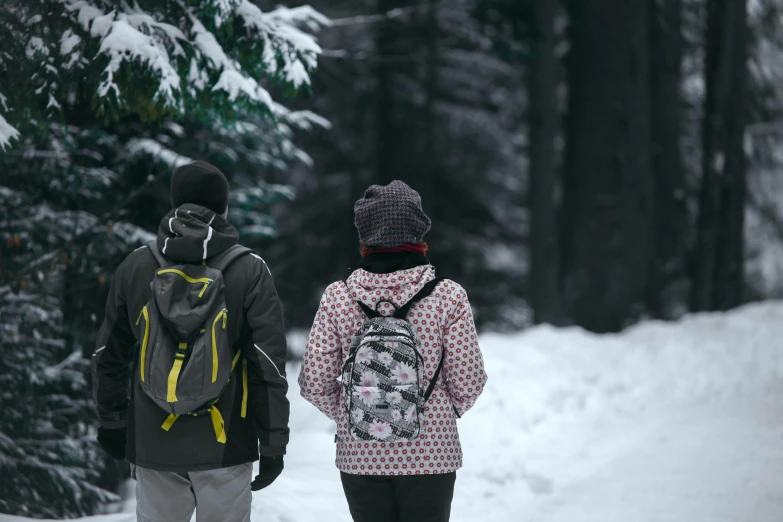 two people walking in the snow with backpacks on