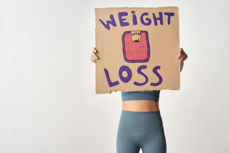 a woman holding a sign that says weight loss