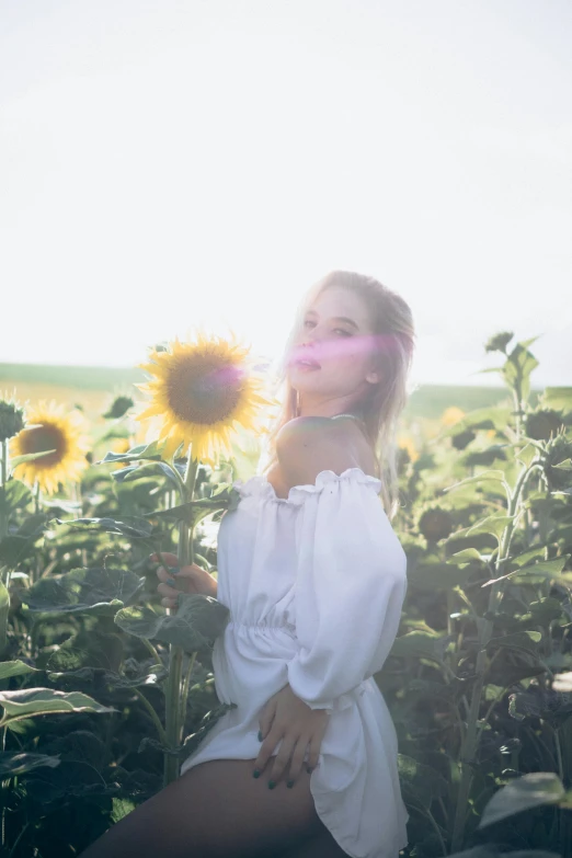 a beautiful young woman posing in the middle of a sunflower field