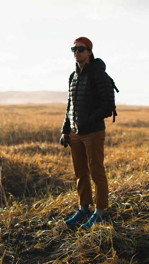 a man standing on the prairie with his hat up and some shoes