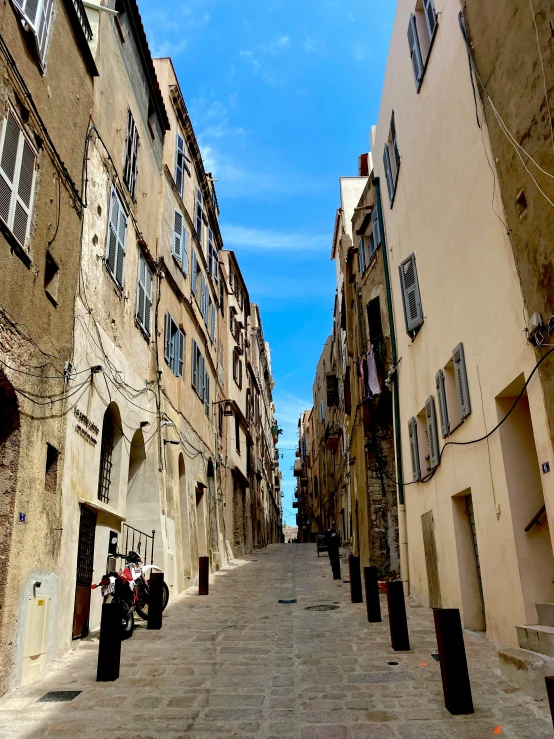 the narrow street is lined with tan buildings