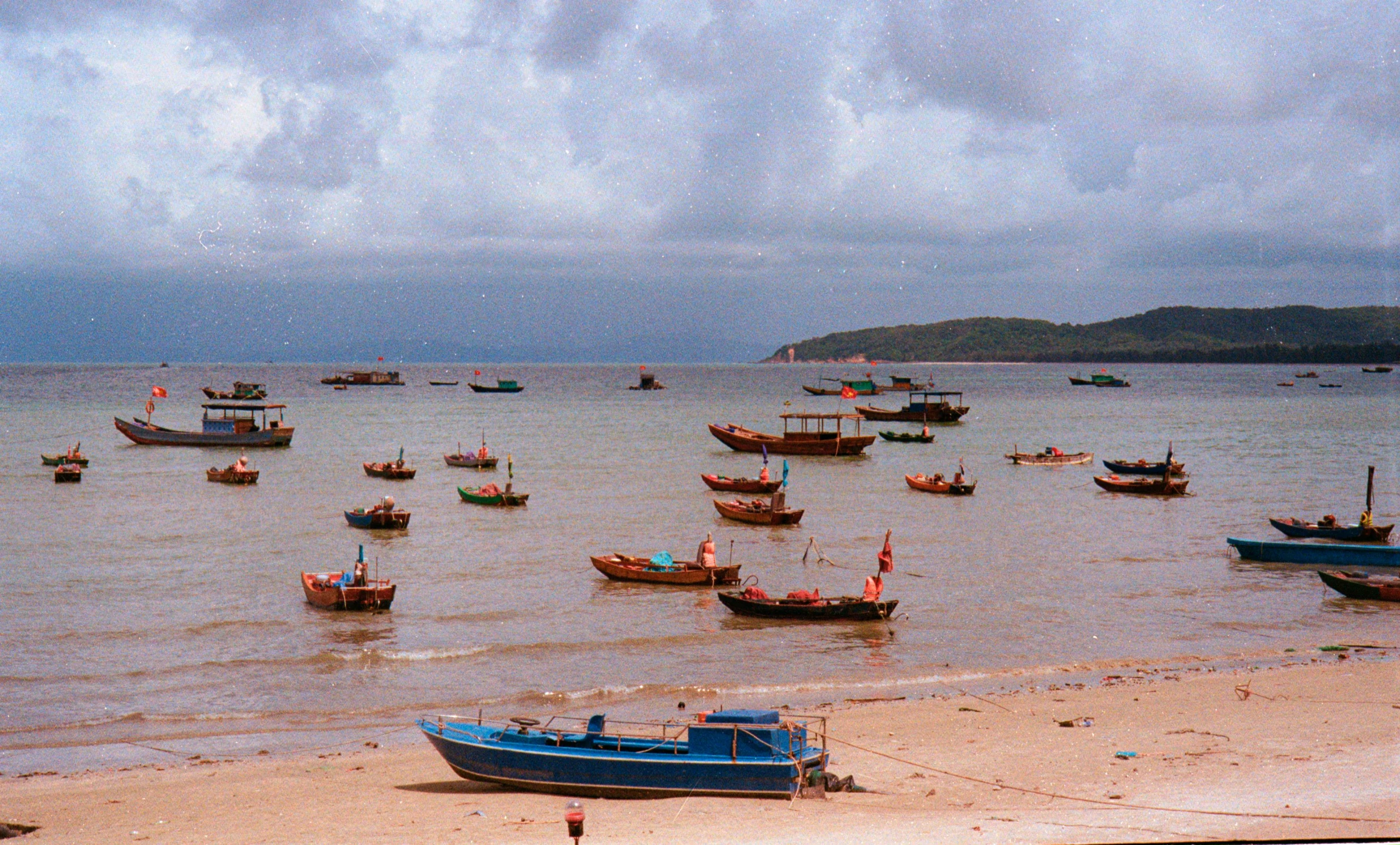 boats in the water on the beach with dark skies