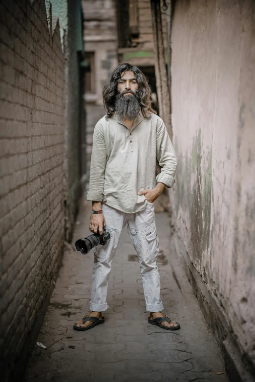 a man standing in an alley with a camera on his hand