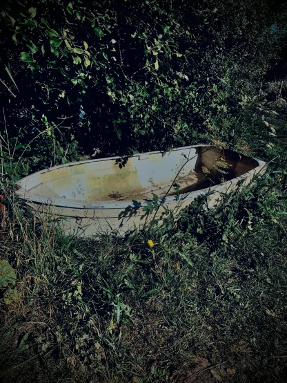 a rowboat lies on the grass next to water